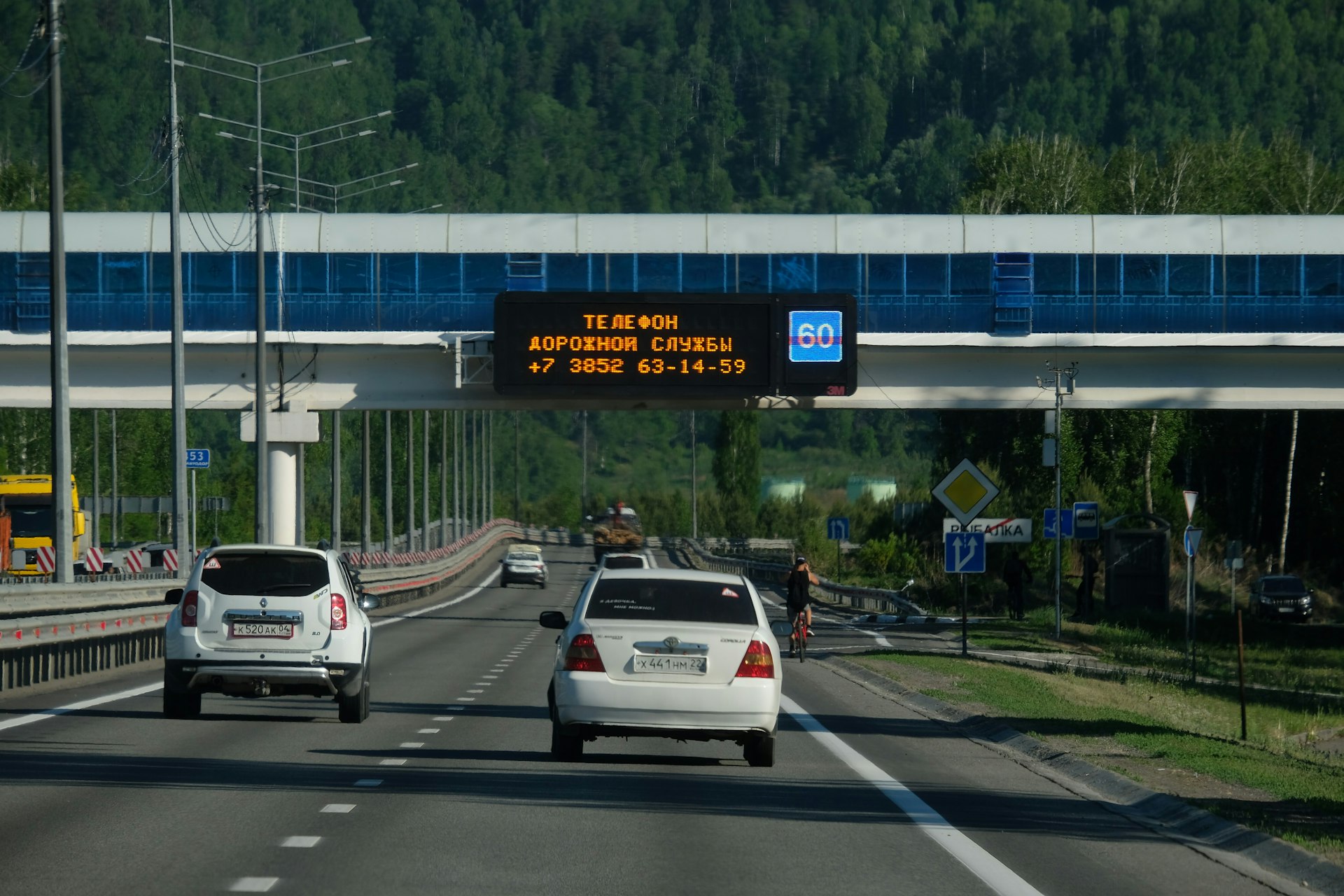 two cars driving down a highway under a bridge