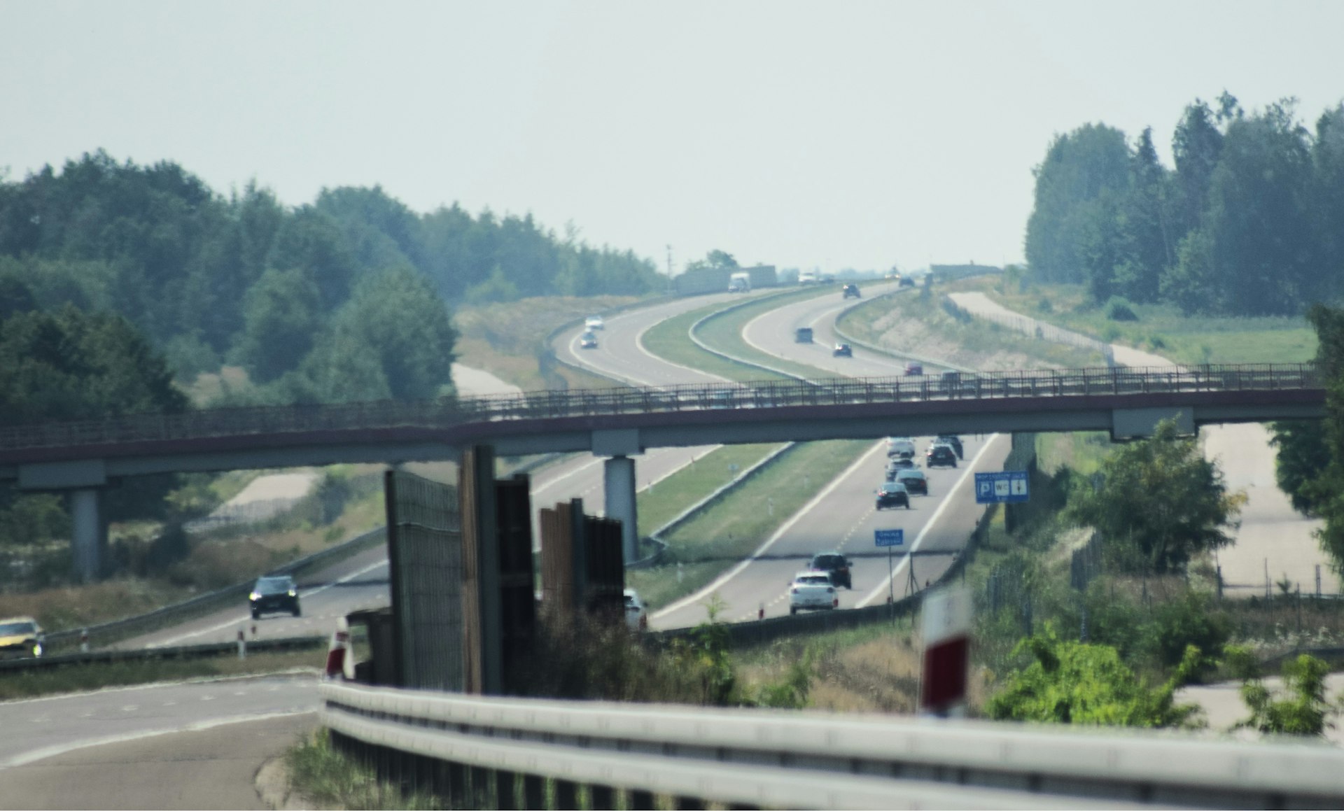 Cars driving on a multi-lane highway passing under a concrete overpass